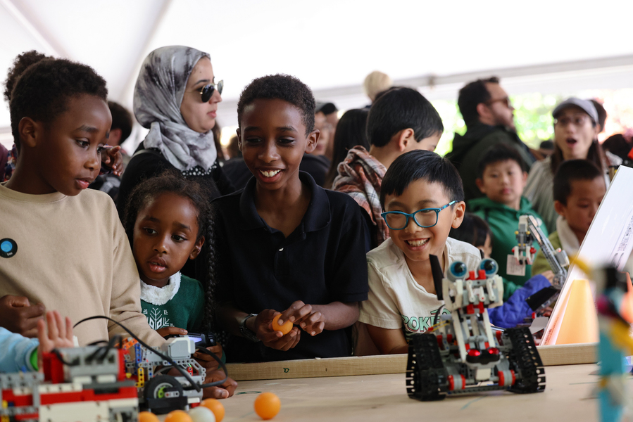 Children participate in a tabletop activity at the Cambridge Science Carnival robot petting zoo.